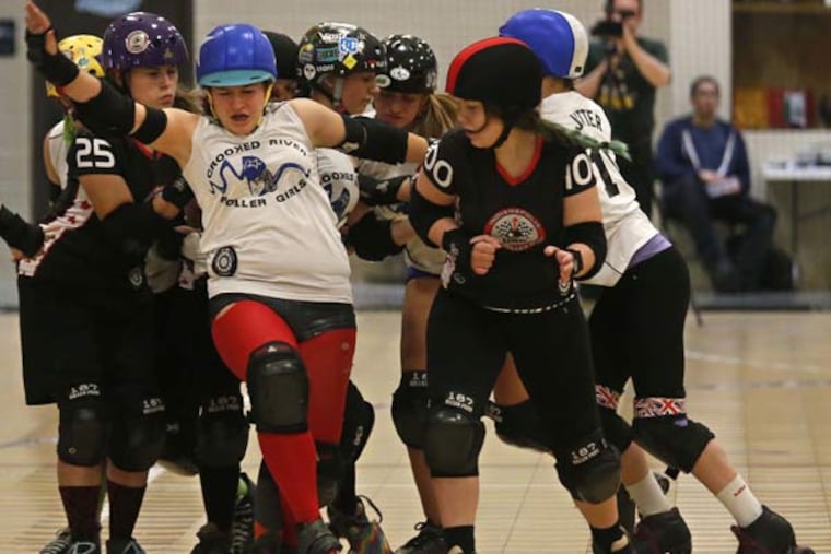 Rayna Fisher, center, a member of the Crooked River Roller Girls roller derby team from Brunswick, Ohio, tries to break away from members of the Indianapolis Junior Roller Derby team during their game in the Great Lakes region of the Junior Roller Derby Association at the Akron Sports Complex on Saturday, May 23, 2015, in Akron, Ohio. (Ed Suba Jr./Akron Beacon Journal/TNS)