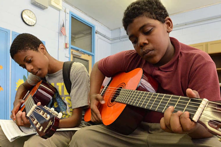 Waring students Tamir Speights (left) and Manard Daniels practice the acoustic guitar.