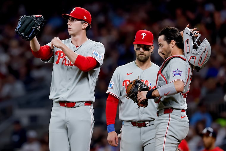 Andrew Painter (left), Bryce Harper, and catcher Garrett Stubbs meet on the mound in the sixth inning on Friday in Atlanta.