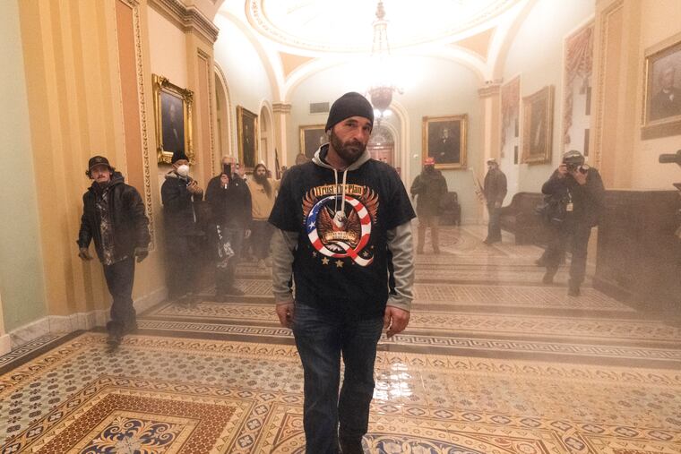 Smoke fills the walkway outside the Senate Chamber as supporters of President Donald Trump, including Douglas Jensen (center) are confronted by U.S. Capitol Police officers on Jan. 6, 2021.