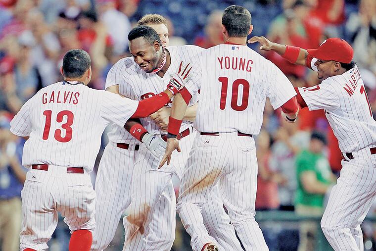 Domonic Brown is swarmed by Phillies teammates after his RBI single ended the game. ( Yong Kim / Staff Photographer )