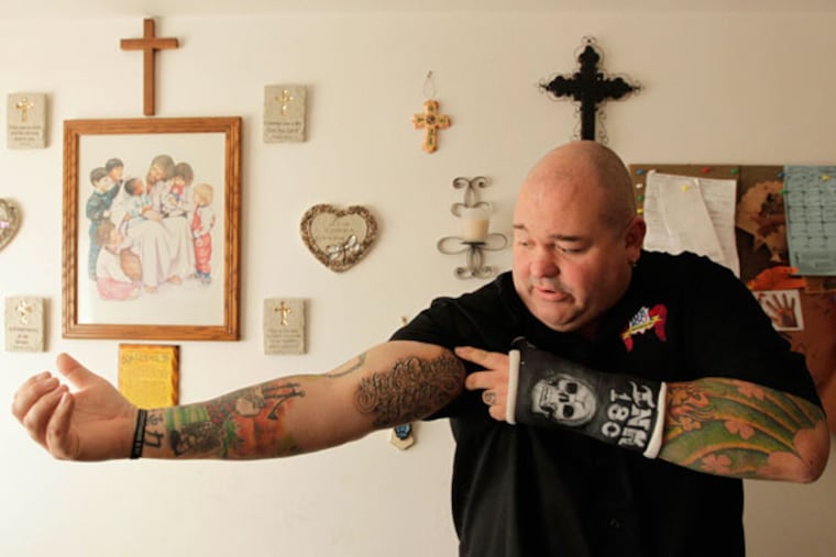 Chris Baker, of Oswego, Illinois, shows his tattoo, "Good Deserves Better," a message related to his Christian beliefs, while in the kitchen of a former prostitute, Nicole, for whom Baker removed a neck tattoo on December 7, 2012. Nicole had been made to wear the tattoo as a kind of "brand" to show she belonged to a pimp. Baker does the work free as part of his cause, "Ink 180." (Chris Walker/Chicago Tribune/MCT)