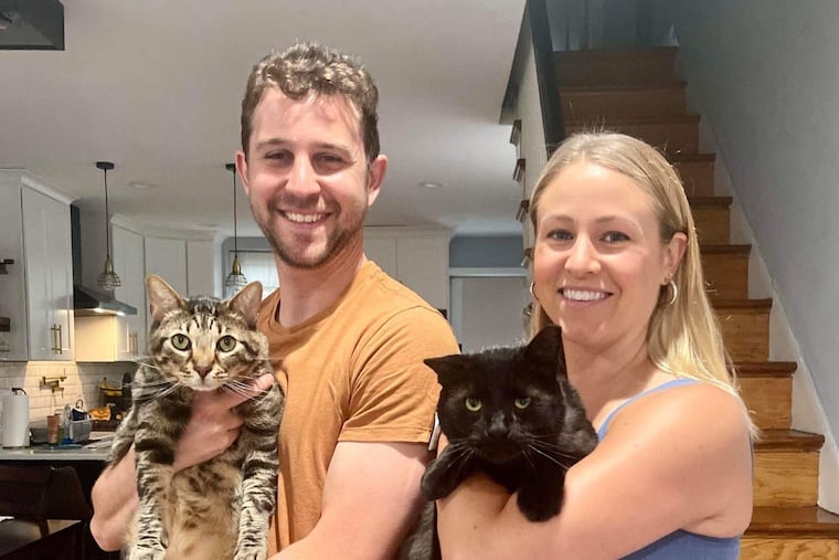 Buddy the cat (right) now has a permanent with Katie Venanzi (right), one of the veterinarians who helped save his life, and her husband, David (left). He will also be living with their tabby cat, Teddy (left).