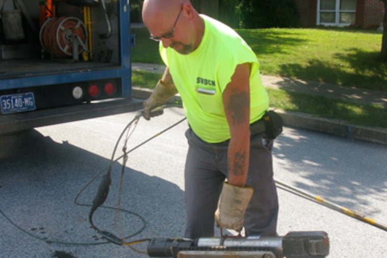 Andrew Brzezicki, sewer maintence operator with the Southwest Delaware County Muncipal Authority, gets ready to lower a camera into an Aston sewer. (Mari A. Schaefer)