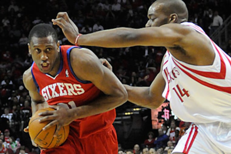 Thaddeus Young drives the ball around Houston Rockets' Carl Landry during the first half. (AP Photo/Pat Sullivan)