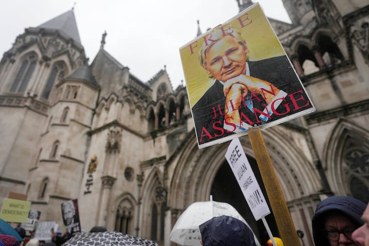 Protesters stand with posters at the Royal Courts of Justice entrance in London on Wednesday.