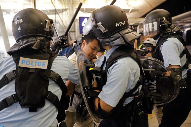Policemen arrest a protester during a demonstration at the Airport in Hong Kong, Tuesday, Aug. 13, 2019. Riot police clashed with pro-democracy protesters at Hong Kong's airport late Tuesday night, a chaotic end to a second day of demonstrations that caused mass flight cancellations at the Chinese city's busy transport hub.