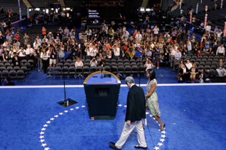 First Lady Michelle Obama walks to center stage with a production manager during a sound check for the Democratic National Convention in Charlotte, N.C., on Monday, Sept. 3, 2012. (AP Photo/Charlie Neibergall)