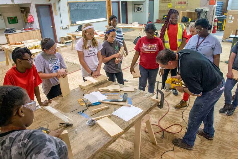 Girls enrolled in Camp MAGIC watch as instructor Tom Millio of the Carpenters Apprentice School demonstrates how to use a saber saw.
