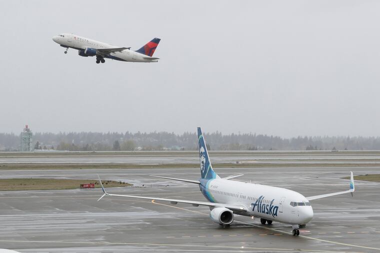 In this April 13, 2018 file photo, a Delta Air Lines plane takes off above a taxiing Alaska Airlines airplane at the Seattle-Tacoma International Airport in Seattle.
