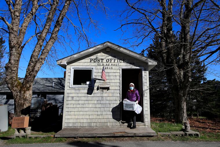 Postmistress Donna DeWitt carries mail at the tiny post office on Isle Au Haut, Maine. The post office serves the 70 or so year-round island residents.