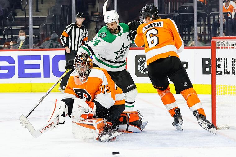 Flyers goaltender Carter Hart stops the puck with teammate defenseman Travis Sanheim against Dallas Stars left wing Jamie Benn during the second period on Monday.