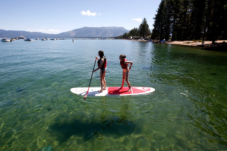 FILE - In this Aug. 20, 2019, file photo, Freya Mayo, left, and her sister Evie, of London, England, try out a paddle board on Lake Tahoe near South Lake Tahoe, Calif. The fallout from humanity's addition to plastics is showing up in the waters of Lake Tahoe. Scientists detected microplastics at several locations around the lake for the first time this year and are working to understand what that means for human health and the environment of the Tahoe Basin. (AP Photo/Rich Pedroncelli, File)