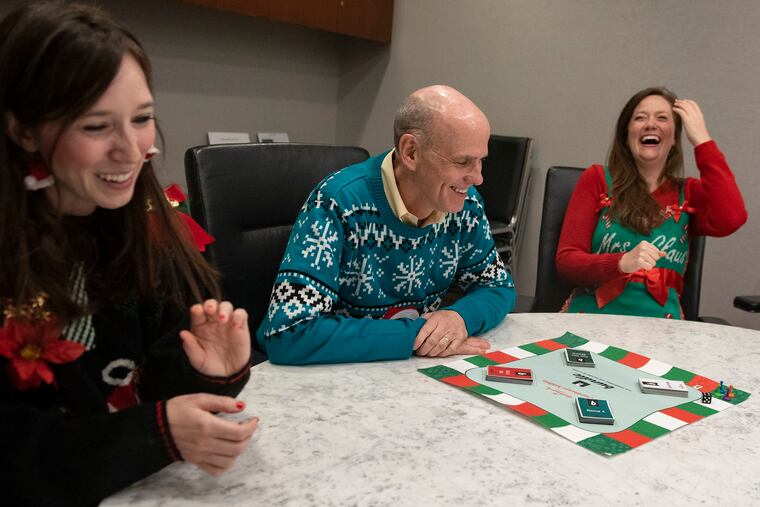 Sisters Cassie Collier, left, and Jacklyn Collier, right, play their Countdown to Christmas Bundle board game with CEO of Crown Media Bill Abbott, center, at the Crown Media - Hallmark Channel headquarters in Midtown Manhattan, NY, in August 2019.