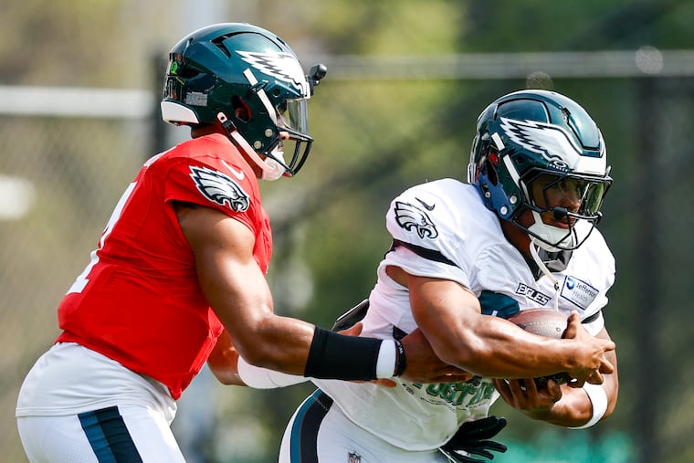Eagles quarterback Jalen Hurts hands off to running back Saquon Barkley during team drills before a joint practice with the New England Patriots on Thursday.