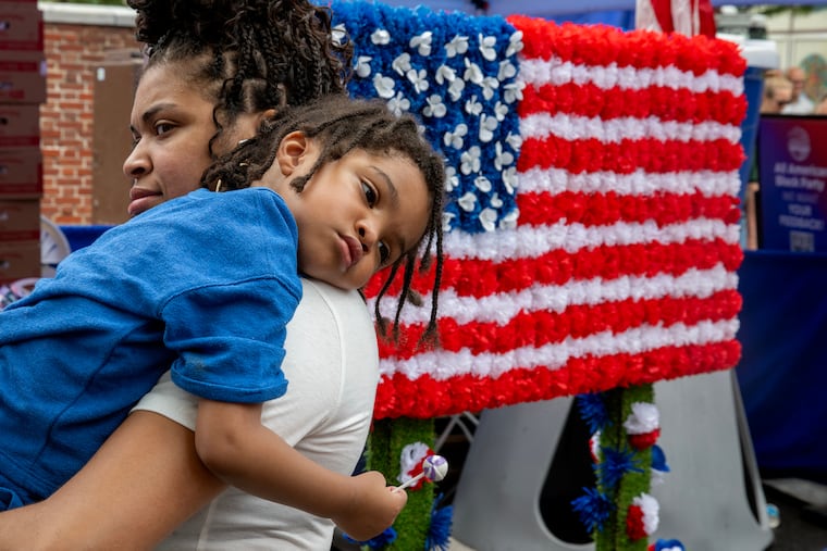 Ciera Brown carries her son, Asaad Neely, 3, as they march in the second annual Red, White, & Blue To-Do parade Wednesday, Jul, 2, 2025, along with whimsical red wagon floats, marching bands, John Adams and Ben Franklin, and representatives from over twenty groups across Philadelphia’s Historic District. The event commemorates a day of “pomp and parade,” as declared by John Adams in 1776. He believed Independence Day would be celebrated on the 2nd - when the Continental Congress officially voted for independence - not two days later when he, John Hancock (and 54 others) signed their document.