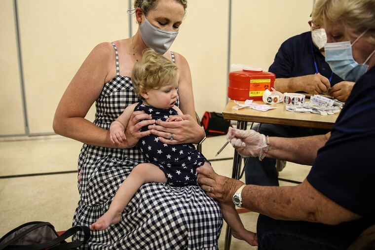 Colleen Neu holds her11-month-old daughter, Abigail, while volunteer Nancy Langerfeld gives her a Moderna COVID vaccine at a at Hatfield Elementary School in June.