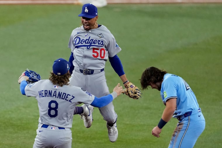The Dodgers' Mookie Betts leaps into the arms of Kiké Hernández after Toronto's Addison Barger was forced out to end Game 6 of the World Series.