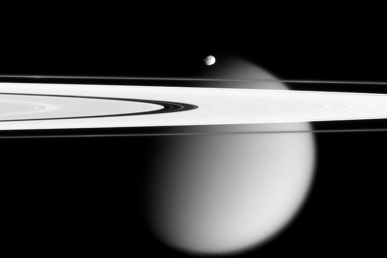 This image made by the Cassini spacecraft and provided by NASA on March 12, 2006, shows two of Saturn's moons, the small Epimetheus and smog-enshrouded Titan, with Saturn's A and F rings stretching across the frame.