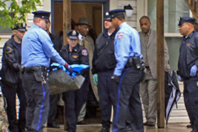 Philadelphia Police remove a bodybag containing a dead baby, still inside a suitcase, after it was found inside a utility shed attached to the rear of a home Monday. (Jim MacMillan / Daily News)