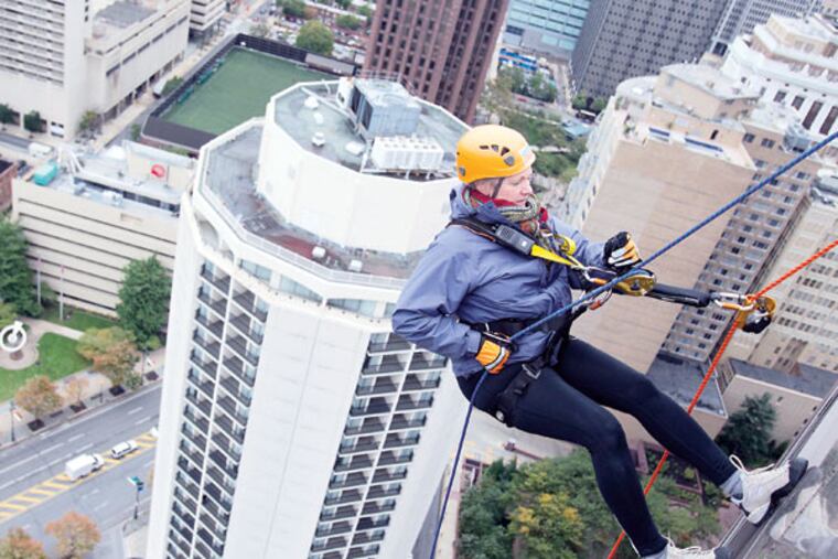 Outward Bound director Katie Newsom Pastuszek begins to rappel down 31 stories at One Logan Square during the two-day fundraiser for the Philadelphia Outward Bound School. MACKENZIE FOX / For The Inquirer