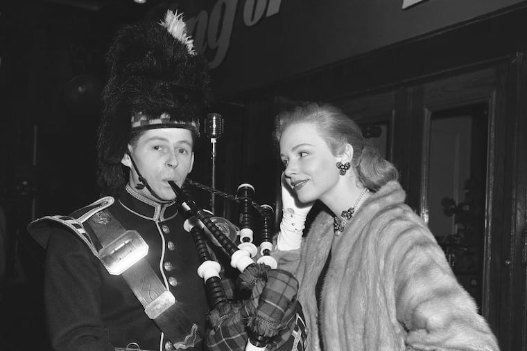 Piper Laurie watches Thomas Gorrian of the Lovat Pipe Band as he pipes a tune before the world premiere of "King of the Khyber Rifles" at the Rivoli Theater in New York in 1953.