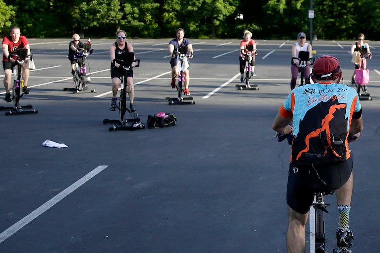 Cycling instructor Tom Hambrose (foreground) leads the 45 minute “Cycling with Tom” spin class in the parking lot at Royal Fitness in Barrington, N.J. on May 27, 2020.
