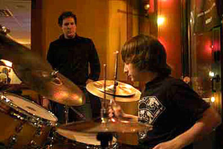 Drum student Eric Jacobs, of Moorestown, performs at Red, Hot & Blue in Cherry Hill, as instructor Patrick Van Belle observes his technique. (John Costello / Staff Photographer)