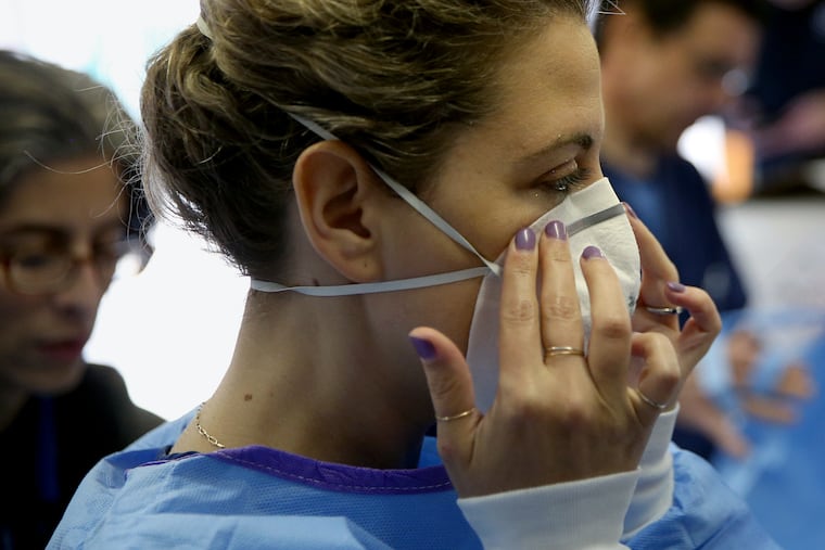 Philadelphia Medical Reserve Corps volunteer and nurse Marina Spitkovskaya puts on a mask before the city's coronavirus testing site opened next to Citizens Bank Park in South Philadelphia on Friday. Protective gear shortages for health care workers are already emerging.