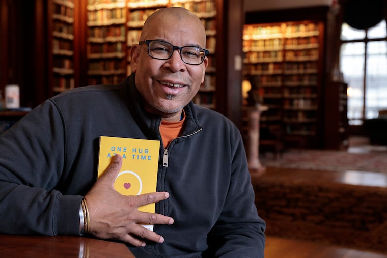 David Hale Sylvester with his new book at the Union League in Philadelphia, where he works as a personal trainer. The SW Philly author is well-known for his cross-country bike and car trips -- during which he hugs or gets a smile from people in every state. He has a new book, 'One Hug at a Time,' chronicles his recent American travels.