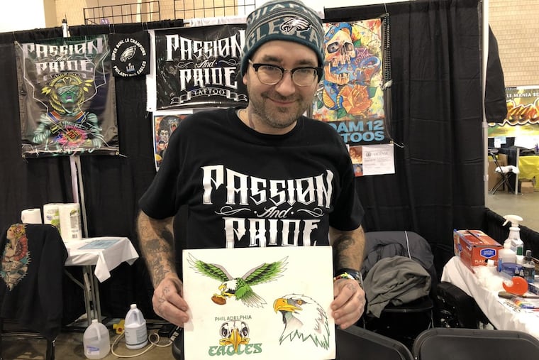 Adam Elliott, of Passion & Pride Tattoo in Cheltenham, holds up his Eagles designs.