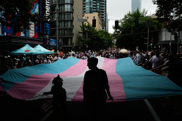 People help carry a transgender pride flag while marching with the University of Washington during the Seattle Pride Parade, Sunday, June 28, 2026, in Seattle. The city's welcoming attitude has brought an influx of trans people from unfriendly red states.