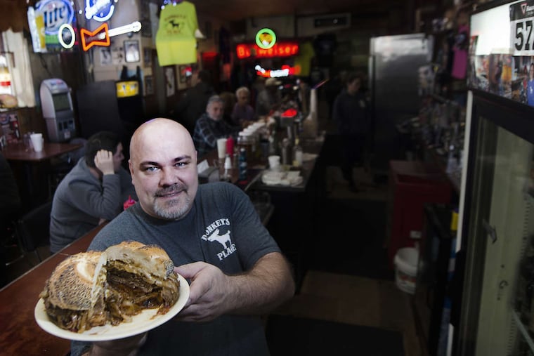 Rob Lucas Jr., third-generation owner of Donkey's Place in Camden, shows off a signature Donkey's cheesesteak at the bar-restaurant's Haddon Avenue location in Camden, N.J.