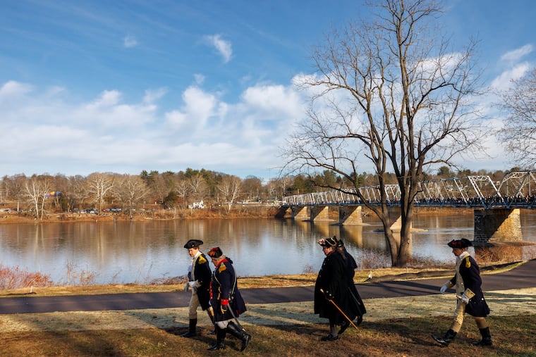 At left is George Washington, played by John Godzieba, who walks with other military officers along the banks of Delaware River. They were there for the reenactment of Washington’s 1776 Christmas night river crossing, Washington Crossing National Park, Washington Crossing, Pa., Thursday, Dec. 25, 2025.