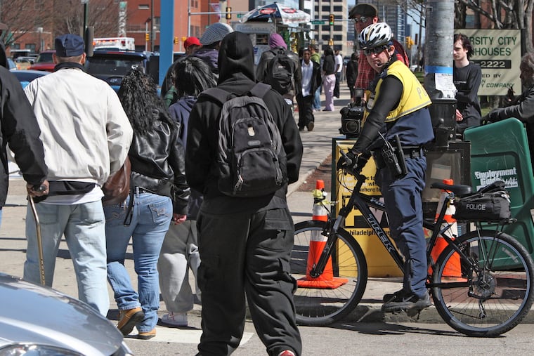 Philadelphia Police officer A.J. Oreo on bicycle patrol at site of rumored flash mob gathering at 40th and Market St., watches as a large group of young people cross 40th St., Mar. 24, 2010.