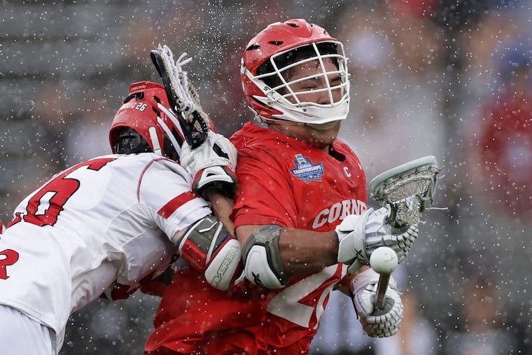 Cornell forward Angelo Petrakis (28) loses the ball after being hit by Rutgers midfielder Zackary Franckowiak during an NCAA Tournament lacrosse semifinals game, Saturday, May 28, 2022, in East Hartford, Conn.