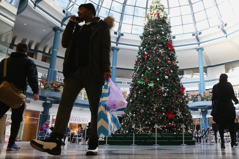 Shoppers walk past the Christmas Tree in the rotunda of the Shops at Liberty Place in Center City this month.