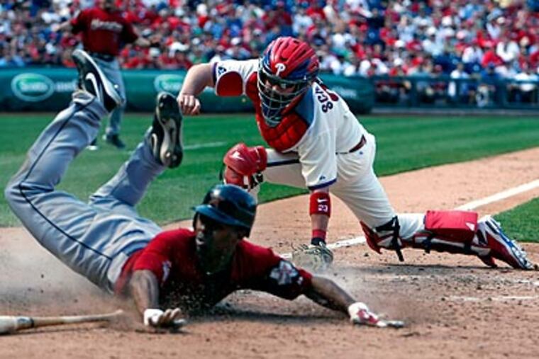 Michael Bourn slides past Brian Schneider's tag in the seventh inning. (Ron Cortes/Staff Photographer)