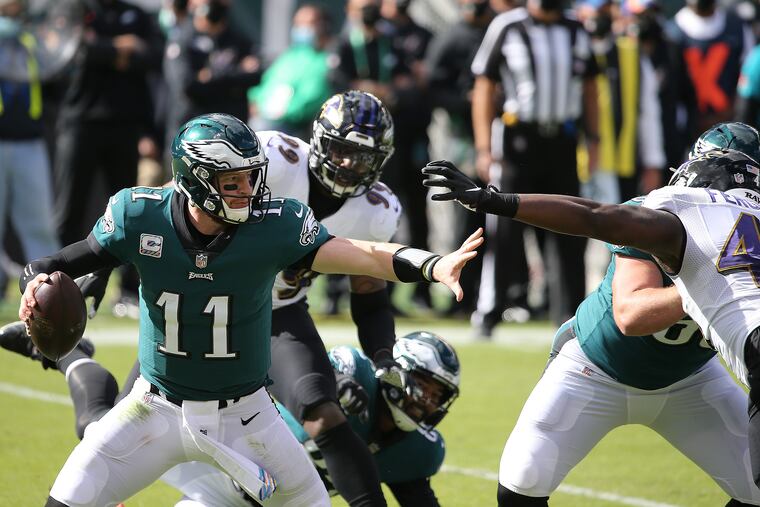 Eagles quarterback Carson Wentz (left) tries to avoid pressure from Ravens linebacker Jaylon Ferguson (right) on Sunday.