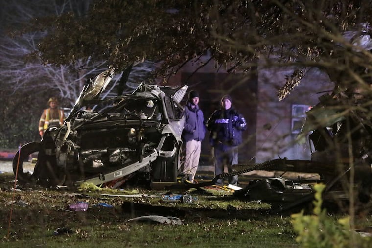 Police and emergency personnel investigate a crash that left a vehicle split in two parts with the front half a burned out shell and the rear wrapped around a tree on Hurffville Road in Deptford.