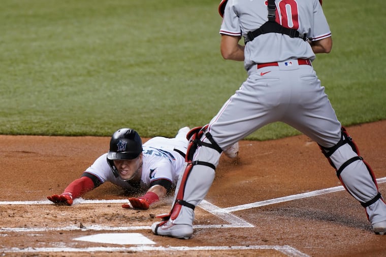 Miami Marlins' Corey Dickerson slides in safely at home to score on a double by Starling Marte as Philadelphia Phillies catcher J.T. Realmuto, right, waits for the throw during the first inning of a baseball game, Thursday, Sept. 10, 2020, in Miami. (AP Photo/Wilfredo Lee)