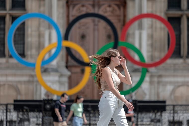 A woman passes by the Olympic rings at the City Hall in Paris last summer.