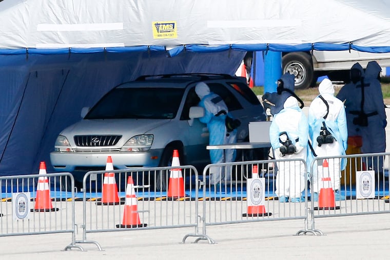 Medical workers perform a test for the coronavirus at Temple University's Ambler campus as Montgomery County opened its drive-through testing site Saturday.