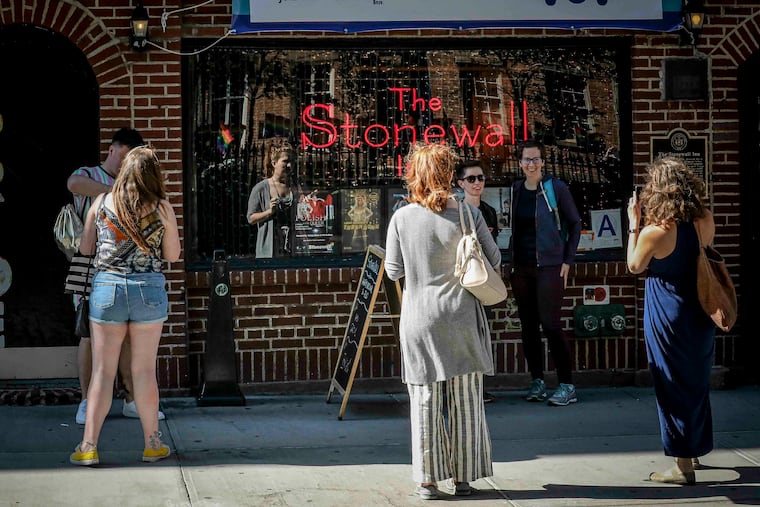 In this Monday, June 3, 2019, photo, visitors pose for photos outside the Stonewall Inn in New York. Fifty years ago, the Stonewall Inn was an underground gay bar where a police raid sparked a rebellion that fueled the modern LGBTQ rights movement. Today, it’s still a bar, but a highly visible one. It’s a landmark, and the patrons flocking in this week to honor the Stonewall riots’ 50th anniversary include a gay police officers’ group.