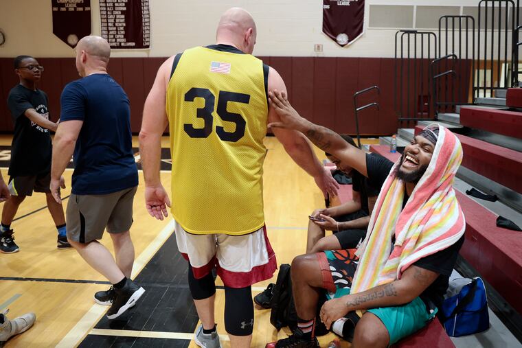 Haverford police Sgt. Rob McCreight (#35) and Quadir Lewis of Darby (right) share a laugh after the basketball game during the Race for Peace at Lower Merion H.S’s Kobe Bryant Gym in Ardmore, Pa. on Fri., Nov. 11, 2022. Race for Peace, which was founded by Andrew Howell, hosts fun events between community members and police to improve engagement and relations.