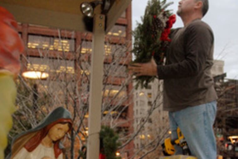 Ancient Order of Hibernians member Tony Nahill affixes a wreath to the Nativity that was vandalized when the baby Jesus was stolen from a creche near Fifth and Market Streets.