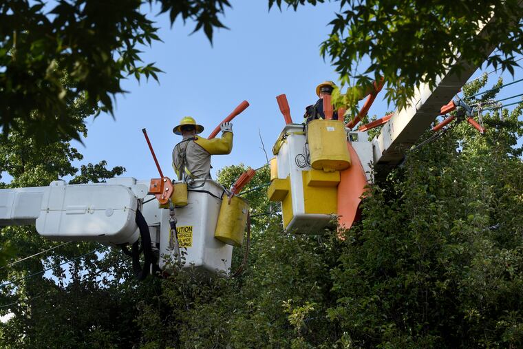Utility crews from PSE&G repair storm damaged power lines in Barrington, N.J., on Wednesday. About 23,000 customers on both sides of the river remain out of power on Friday, down from about 700,000 impacted by the storm on Tuesday.