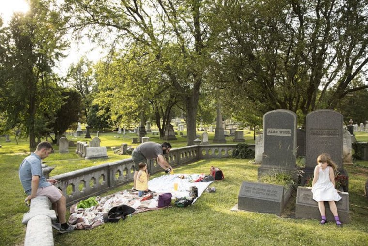 A family sets up for a picnic in the Woodlands cemetery in West Philly, which hosts a number of events to attract new visitors to its historic grounds.