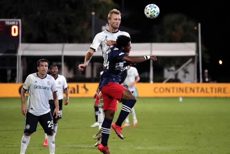 Union forward Kacper Przybylko going up for a header against New England Revolution forward DeJuan Jones (front) during the MLS tournament's round of 16.