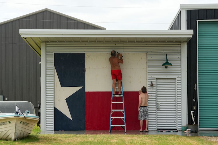Clyde George, left, and his son Chris board up their home in Port O'Connor, Texas, on Sunday, July 7, 2024.